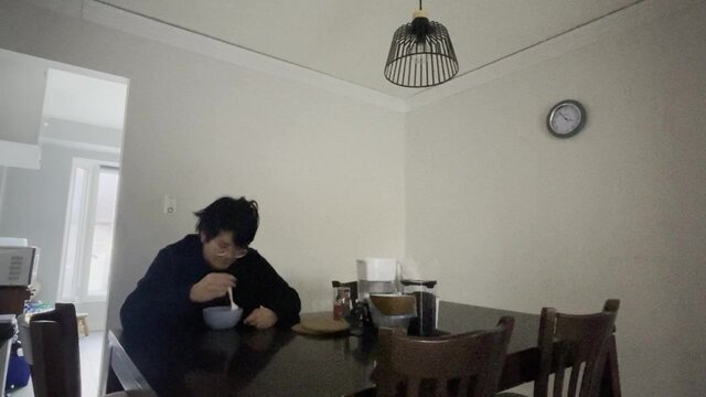 Unhappy Asian teenager cries while eating cereal alone in the dark,